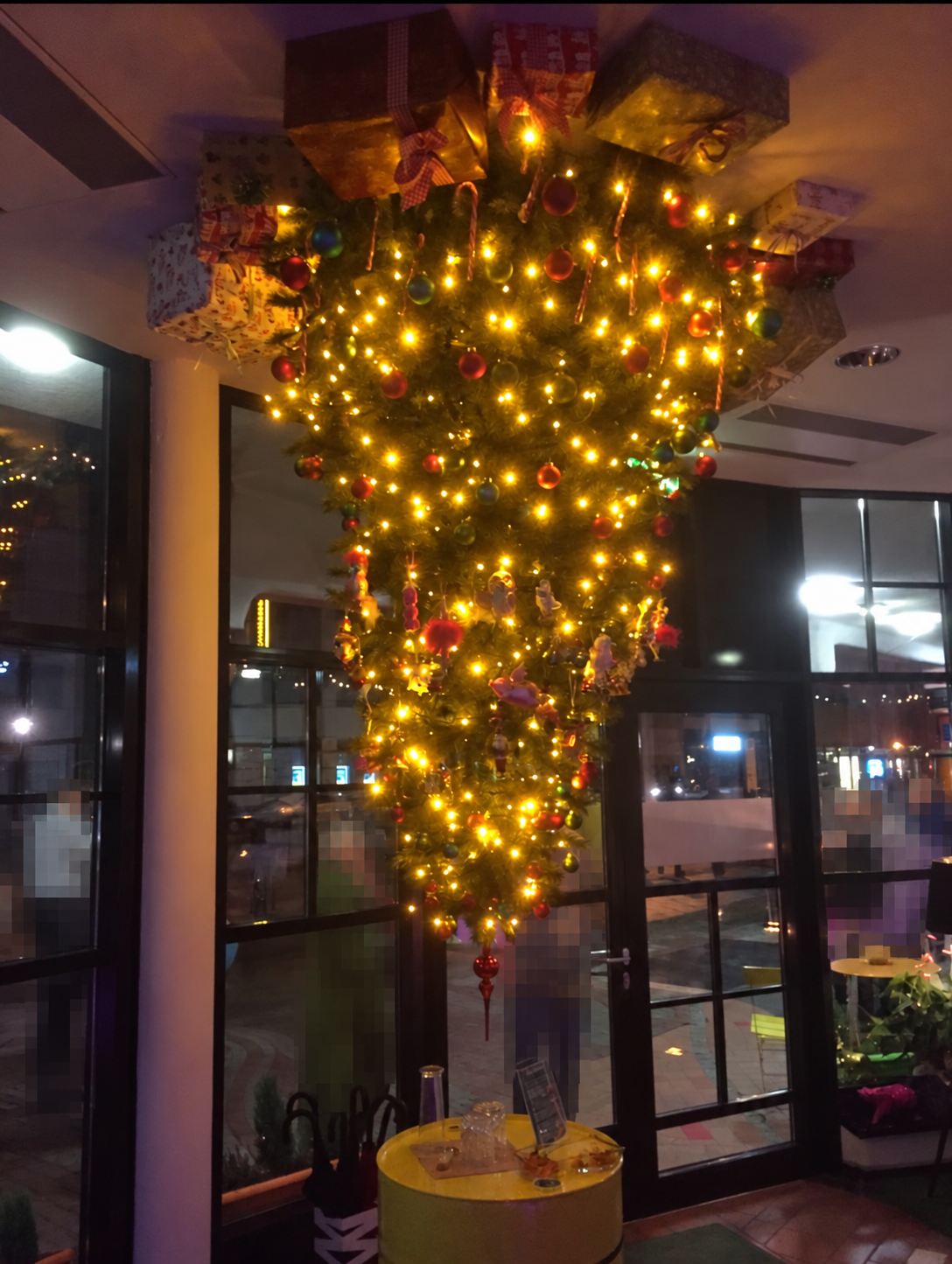 Nuestro árbol de Navidad, adornado con luces cálidas y bolas, cuelga boca abajo del techo del vestíbulo.